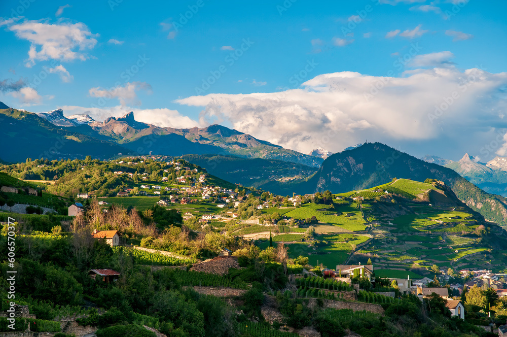Idyllic Highlands near Sion, Switzerland at sunny summer day. Tranquility of the rolling hills adorned with charming farmhouses and lush vineyards, creating a serene and idyllic scene