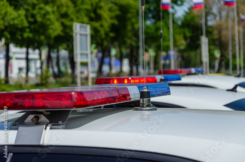 Police car flashing light. In the background, the flags of Russia are out of focus.