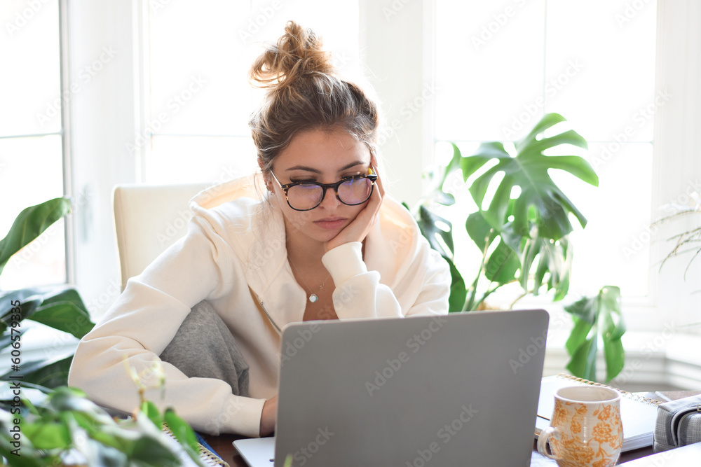 Young teenage girl student using laptop computer while studying at home