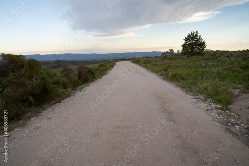 View of the empty dirt road across the hills at sunset.