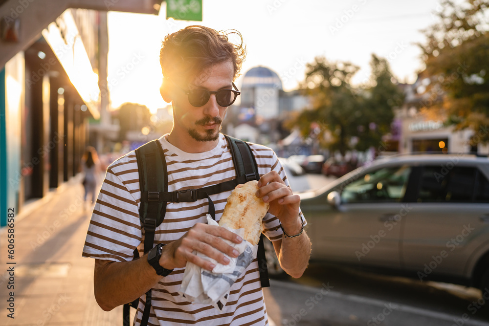 Φωτογραφία One man young adult modern caucasian male in the city in sunny day walk and eat