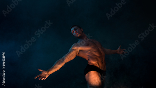 A muscular athlete in an epic pose arms outstretched, fog and smoke on the background, warm mystical light from below, the concept of the antique beauty of the human body