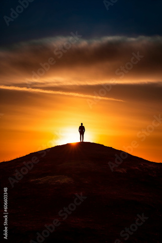 A dramatic silhouette of a person standing on a hill. AI generative