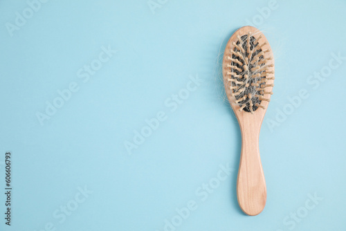 Wooden brush with lost hair on light blue background, top view. Space for text