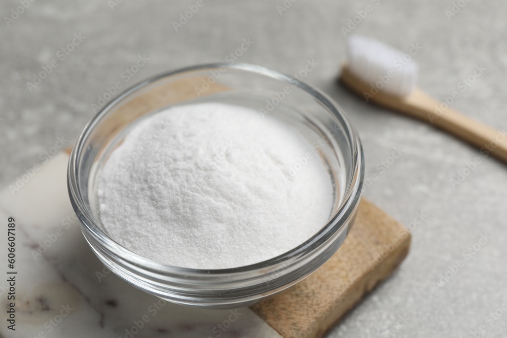 Bamboo toothbrush and bowl of baking soda on grey table, closeup Bamboo toothbrush and bowl of baking soda on grey table, closeup