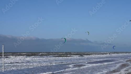 Many people enjoy riding kite surf board in windy day at sea ocean shore kitesurfing the Hague beacht. Watersport adrenaline fun adventure acitivity photo