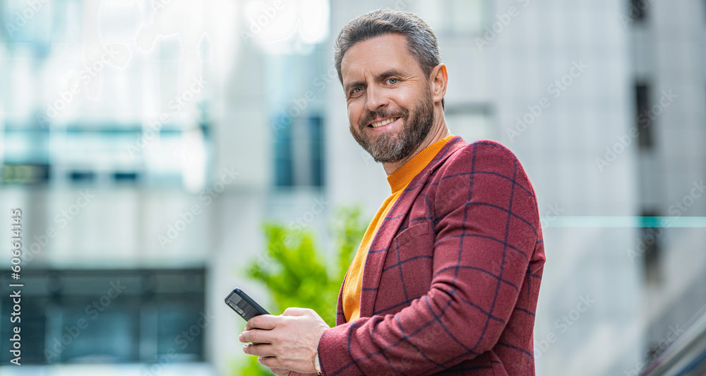 happy man texting on smartphone outdoor. man texting on smartphone in the street. happy man texting on smartphone outdoor. man texting on smartphone in the street.