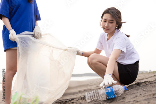 Young student collecting plastic waste on the beach. People cleaning the beach up