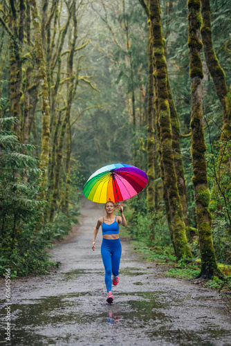 Woman runner with rainbow umbrella in a forest