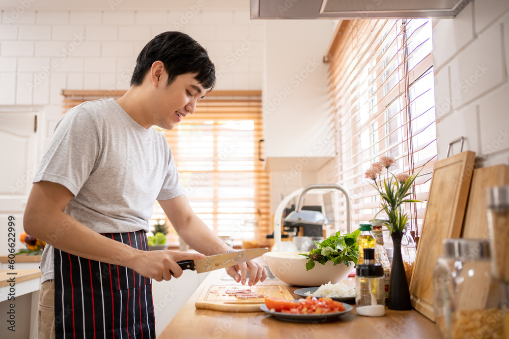 Taking care of his health. Handsome young man in casual wear smiling while standing in the kitchen at home Taking care of his health. Handsome young man in casual wear smiling while standing in the kitchen at home