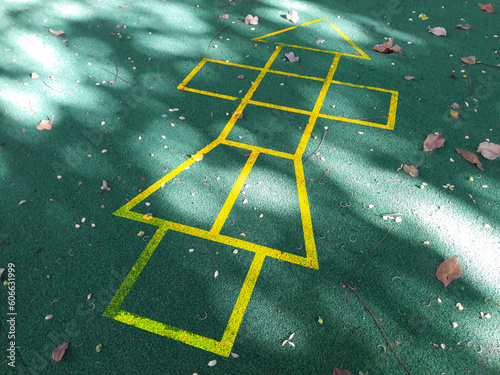 Painted yellow lines contrast against the dark asphalt and form the classic school playground game of Hopscotch photo