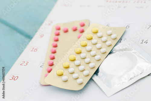 Contraceptive control pills and condom on date of calendar background calculate date Control the birth rate. health care and medicine, contraception concept. empty space for text.