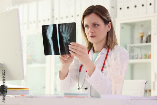 Doctor studies X-ray picture of patient arm sitting at table