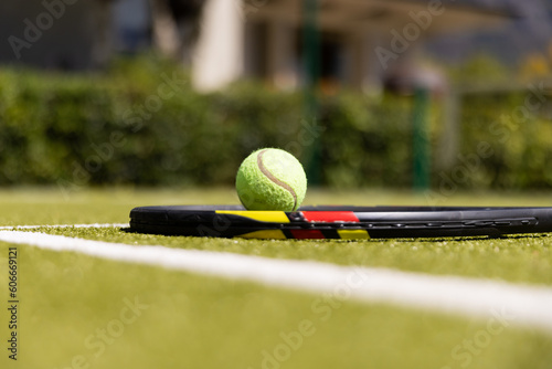 Close-up of tennis racket and ball by white marking on grassy field at tennis court