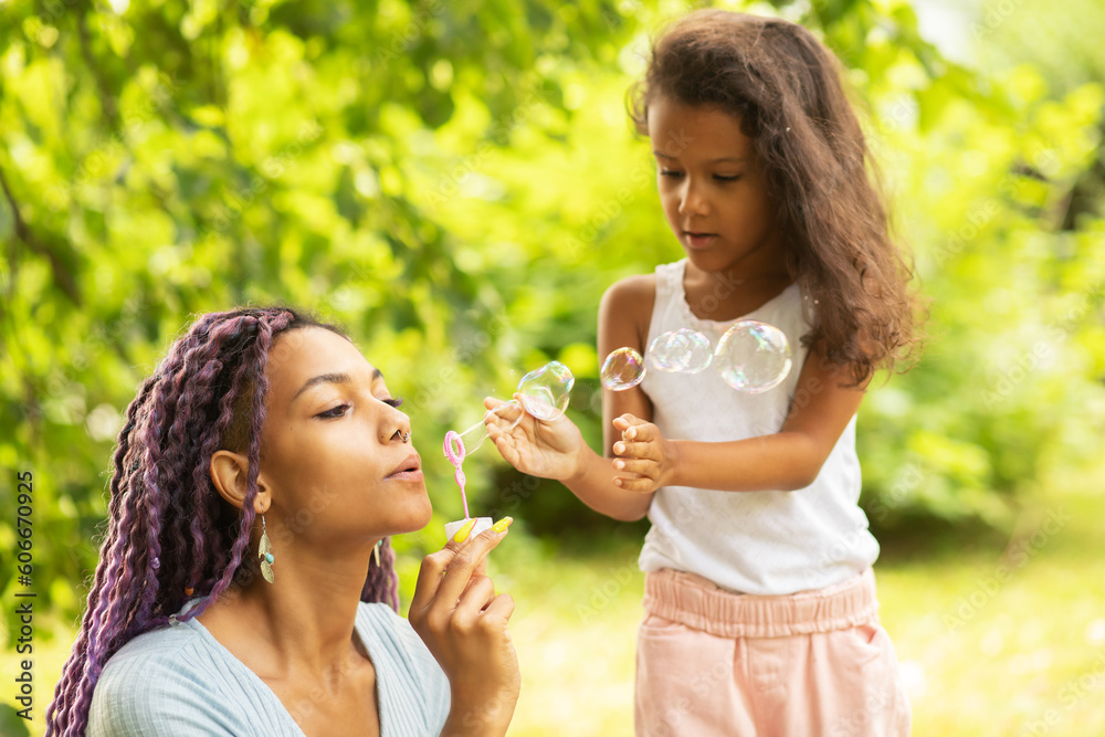 mother with daughter in the park, african young woman with child playing with soap bubbles in nature, family spending time together, happy kid with single parent mother with daughter in the park, african young woman with child playing with soap bubbles in nature, family spending time together, happy kid with single parent