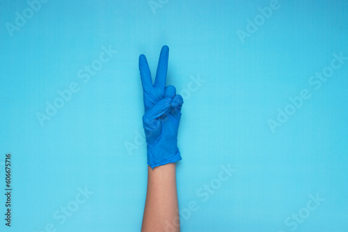 hand in blue medical glove making hand gesture on light blue background