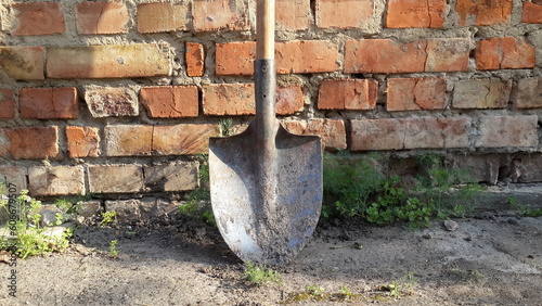 old dirty shovel on brick wall background. garden tools equipment. agriculture tool concept 