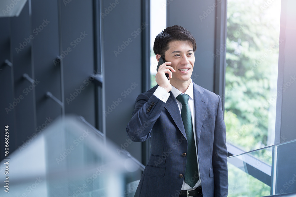 Handsome Asian (Japanese) businessman in suit making a phone call Business scene Handsome Asian (Japanese) businessman in suit making a phone call Business scene