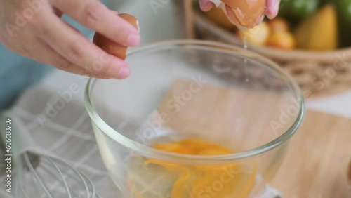 Young woman cooking in a bright kitchen, hand made cracked fresh egg yolks dripping into the bowl. Preparing ingredients for healthy cooking. Homemade food