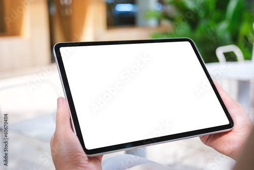 Mockup image of a woman holding digital tablet with blank white desktop screen in the outdoors cafe