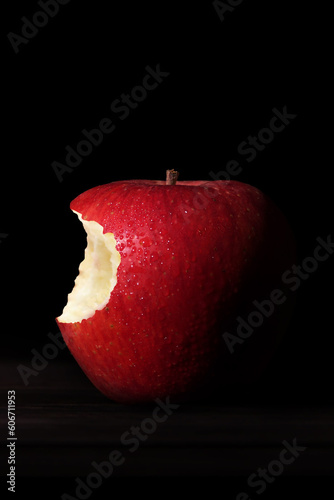 Manzana roja mordida sobre fondo negro. 