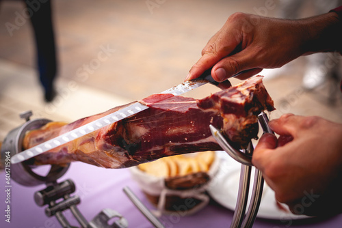 Manos cortando con cuchillo lonchas de jamón de cerdo
