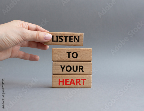 Listen to your heart symbol. Concept word Listen to your heart on wooden blocks. Beautiful grey background. Businessman hand. Business and Listen to your heart concept. Copy space