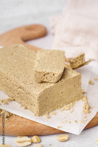 Board with tasty halva and peanuts on white background