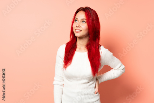 Teenager red hair girl isolated on pink background thinking an idea while looking up