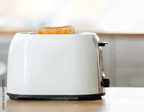 Modern toaster with crispy bread slices on table in kitchen