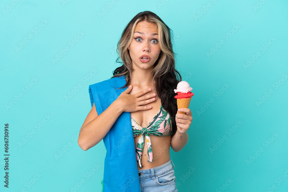 Teenager caucasian girl holding ice cream and towel isolated on blue background surprised and shocked while looking right Teenager caucasian girl holding ice cream and towel isolated on blue background surprised and shocked while looking right