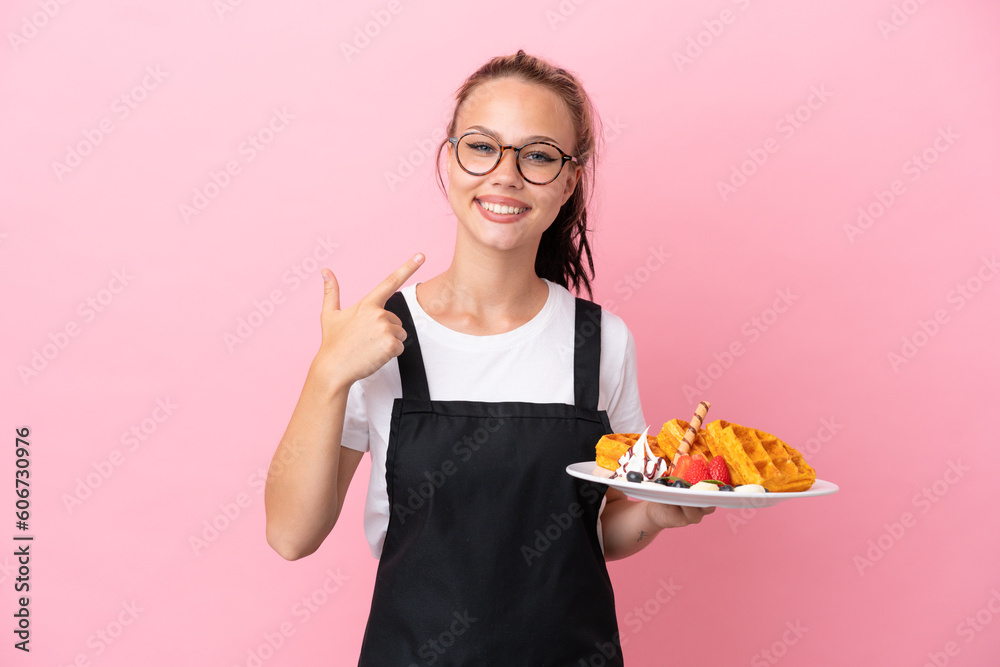 Restaurant waiter Russian girl holding waffles isolated on pink background giving a thumbs up gesture Restaurant waiter Russian girl holding waffles isolated on pink background giving a thumbs up gesture
