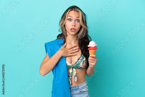 Teenager caucasian girl holding ice cream and towel isolated on blue background surprised and shocked while looking right