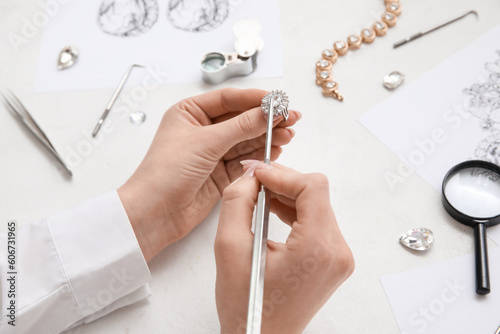 Female jeweler making ring on white table, closeup