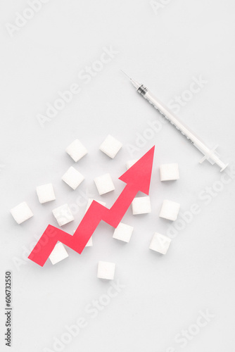 Sugar cubes with syringe for insulin injection and arrow directed upwards on white background