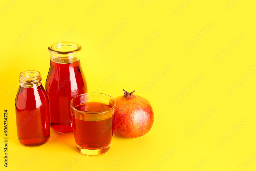 Bottles and glass of fresh pomegranate juice on yellow background Bottles and glass of fresh pomegranate juice on yellow background