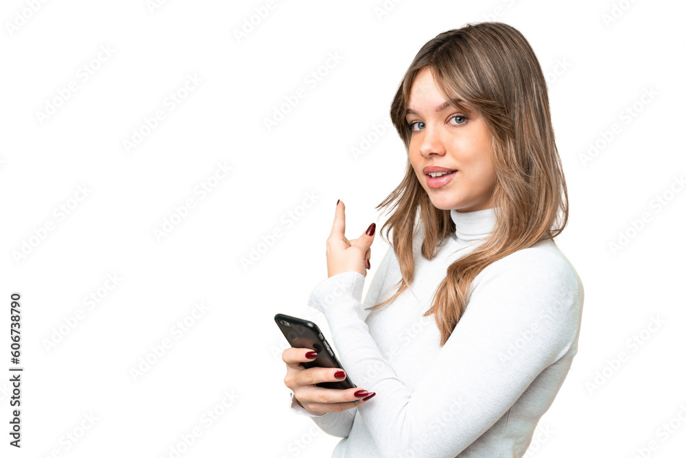 Young girl over isolated chroma key background using mobile phone and pointing back Young girl over isolated chroma key background using mobile phone and pointing back
