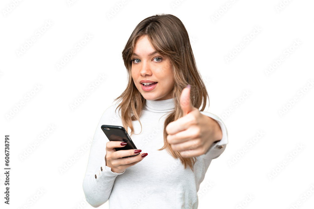 Young girl over isolated chroma key background using mobile phone while doing thumbs up Young girl over isolated chroma key background using mobile phone while doing thumbs up