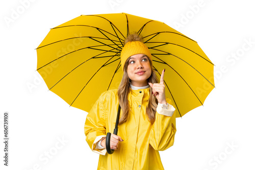 Young girl with rainproof coat and umbrella over isolated chroma key background pointing up a great idea