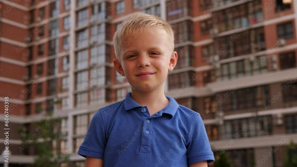 Portrait of a little boy in the courtyard of a modern multi-storey building in summer. A child walks in the city in the summer. Portrait of a little boy in the courtyard of a modern multi-storey building in summer. A child walks in the city in the summer.