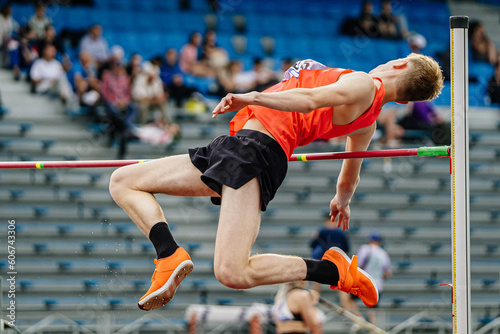 close-up male athlete jumper high jump in summer athletics championships, fosbury flop technique