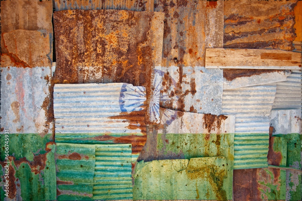 Flag of India on rusty corrugated iron sheets forming a wall or a fence