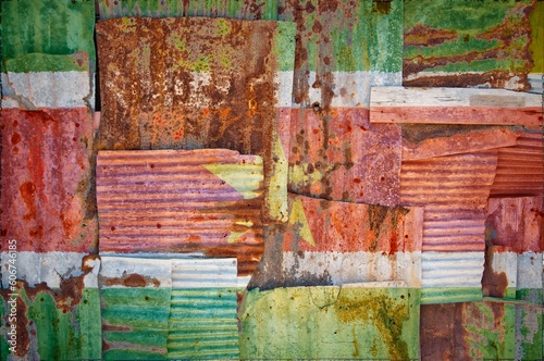 Flag of Suriname painted onto rusty corrugated iron sheets overlapping to form a wall or fence © Tonygers/Wirestock Creators