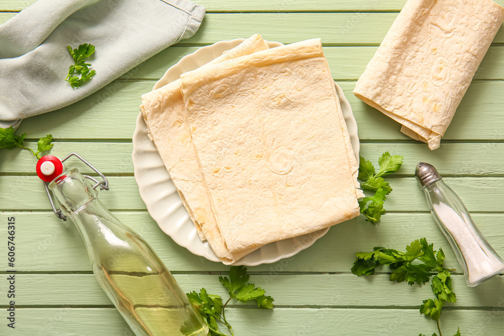 Plate with fresh lavash on green wooden background