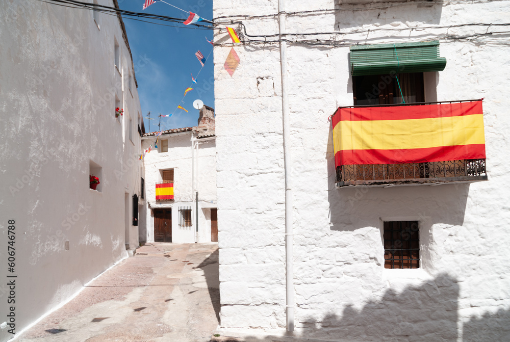 Fototapeta premium Vista de las calles blancas de un típico pueblo español con la bandera de España.