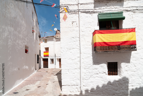 Vista de las calles blancas de un típico pueblo español con la bandera de España. photo
