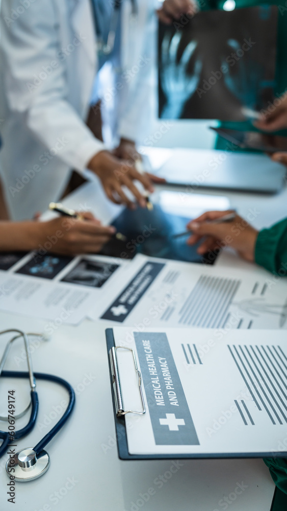 Φωτογραφία Medical surgical team meeting with doctors in white lab coats and surgical gowns sitting at table discussing x-ray of patient history
