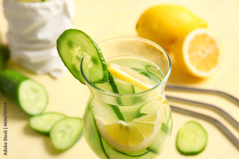 Glass of infused water with cucumber slices on yellow background Glass of infused water with cucumber slices on yellow background