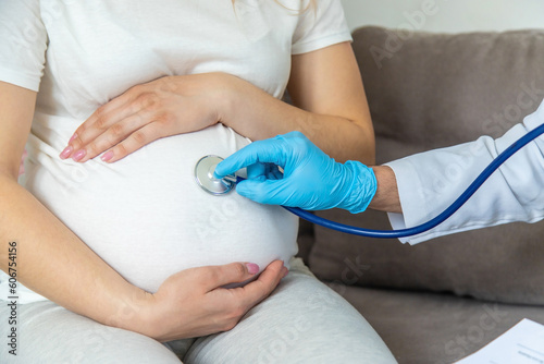 The doctor examines the belly of a pregnant woman. Selective focus.