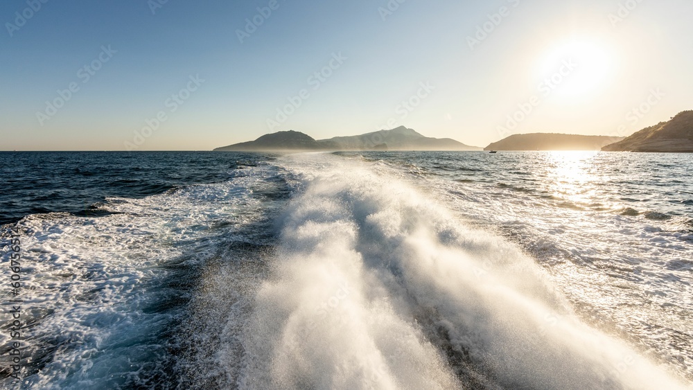 Foam in the back of a boat in seawater under sunny sunset